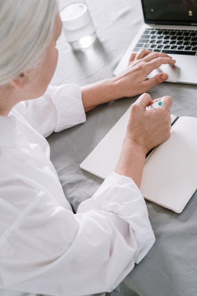 pexels-photo-4057764 Elderly woman takes notes while using a laptop at home.